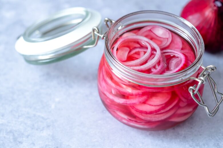 Pickled,Red,Onions,In,Glass,Jar,On,A,Gray,Background.