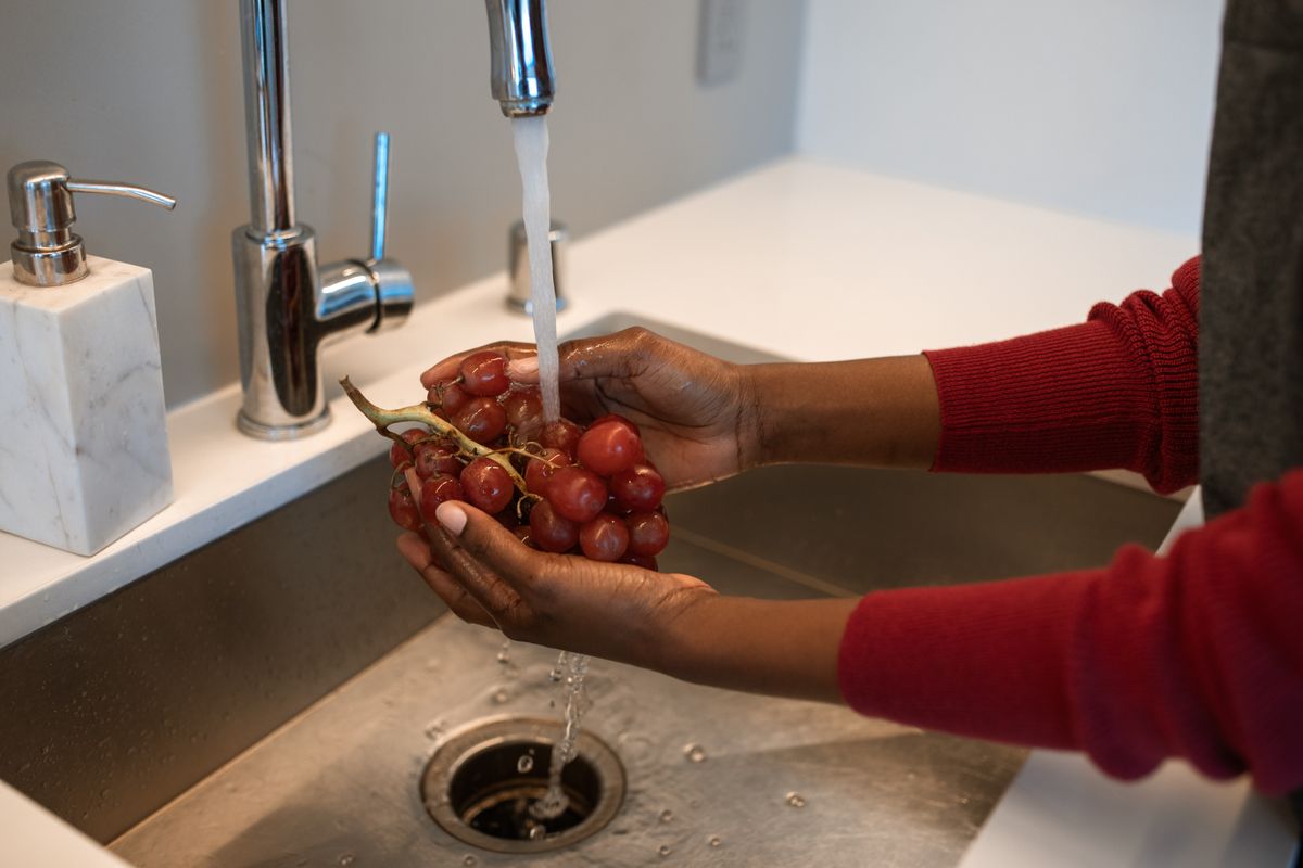 Uve rosse fresche vengono lavate nel lavandino della cucina Uve rosse fresche vengono lavate nel lavandino della cucina