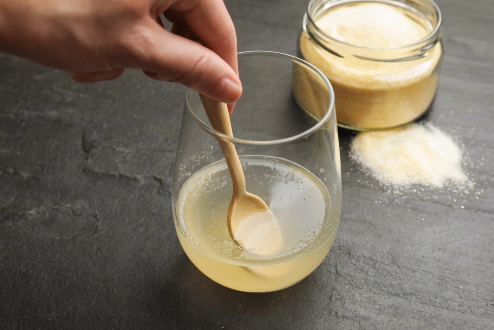Woman,Stirring,Bloomed,Gelatin,With,Spoon,At,Dark,Textured,Table, Woman,Stirring,Bloomed,Gelatin,With,Spoon,At,Dark,Textured,Table,