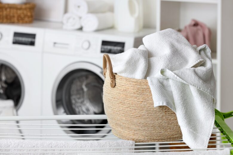 Freshly,Washed,White,Towels,In,Woven,Laundry,Basket,On,Drying