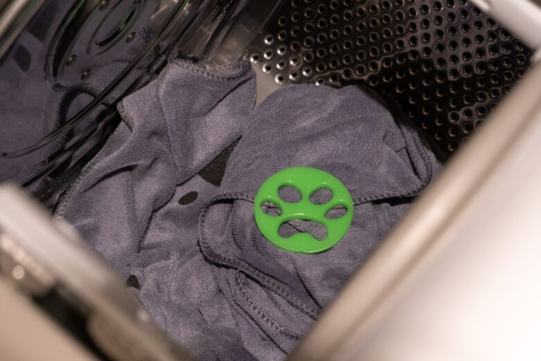 Interno della lavatrice con caricato abbigliamento grigio e accessorio per raccogliere peli di animale